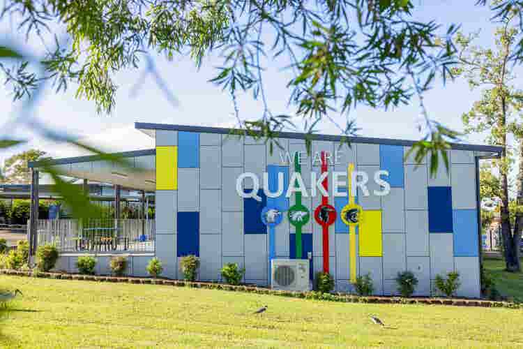 Photo of the school building with the words We are Quakers featuring the School Houses Logo